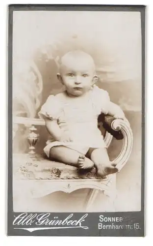 Fotografie Alb. Grünbeck, Sonneberg, Bernhardstr. 15, Portrait niedliches Baby auf einem Stuhl