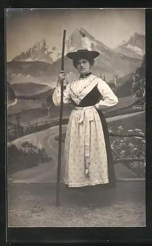 Foto-AK Studiokulisse, Frau im Trachtenkleid mit Hut und Wanderstock
