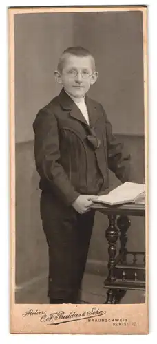 Fotografie Atelier C. F. Beddies & Sohn, Braunschweig, Kuh-Str. 10, Portrait Knabe mit Brille und aufgeschlagenem Buch