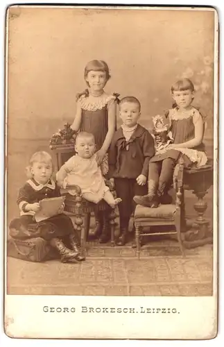 Fotografie Georg Brokesch, Leipzig, Portrait vier hübsch gekleidete Kinder mit Kleinkind und Puppe