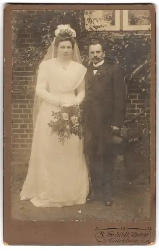 Fotografie R. Schildt, Quickborn, Portrait bürgerliches Paar in Hochzeitskleidung mit Blumenstrauss