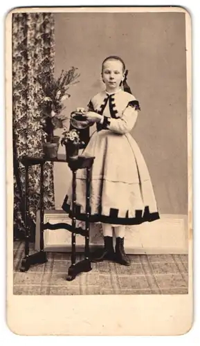 Fotografie Hermann Hampel, Schönlinde, Mädchen im Sonntagskleid giesst Blumen mit einer Giesskanne