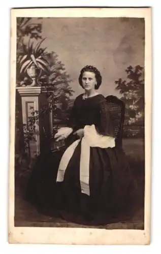 Fotografie unbekannter Fotograf und Ort, Portrait junge Frau im schwarzen Kleid mit Fotoalbum auf dem Schoss