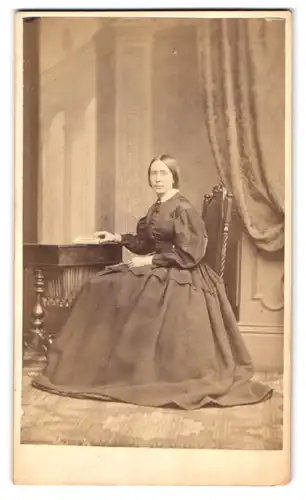 Fotografie Ja. Robertson, Glasgow, Sauchihall 76, Portrait junge schottin im Biedermeierkleid sitzend am Tisch
