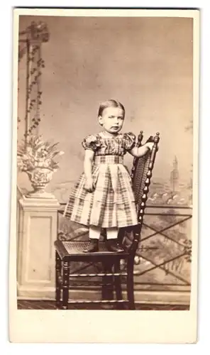 Fotografie W. Ernst, Hannover, Perlstr. 6, Portrait niedliches Mädchen im karierten Kleid stehend auf einem Stuhl