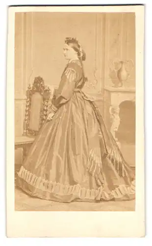 Fotografie C. Schwartz & Co., Berlin, Mohrenstr., Portrait junge Frau im Biedermeierkleid steht seitlich im Atelier