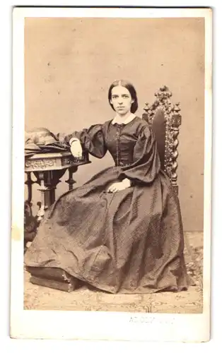 Fotografie Adolf Ost, Wien, Landstr., Portrait junge Frau im gemusterten Kleid sitzend im Atelier