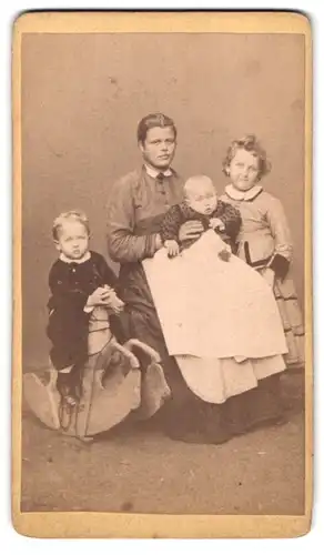 Fotografie unbekannter Fotograf und Ort, Portrait junge Dame mit Baby und zwei Kindern mit Schaukelfperd