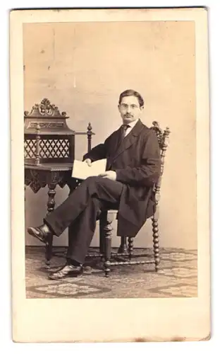 Fotografie G. Steffons, Berlin, Potsdamer Str. 116a, Portrait junger Mann im dunklen Anzug mit einem Buch am Sekretär