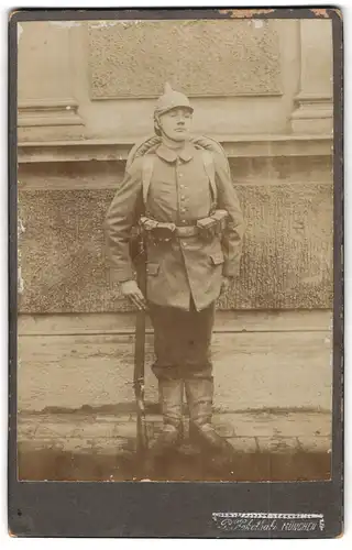 Fotografie P. Kohothaki, München, Soldat in Feldgrau mit Gewehr, Pickelhaubenüberzug, Kriegsausmarsch