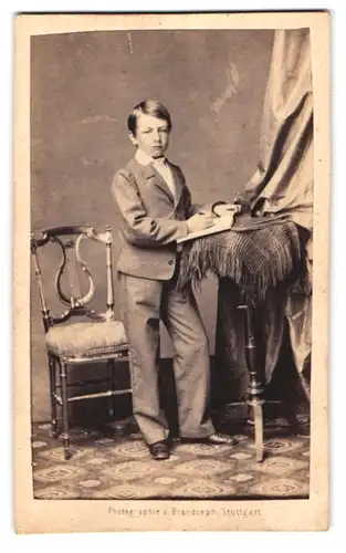 Fotografie v. Brandseph, Stuttgart, Portrait hübscher Knabe im Anzug mit Buch