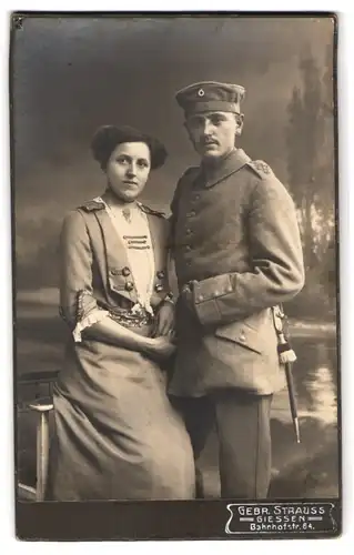 Fotografie Gebr. Strauss, Giessen, Bahnhofstr. 64, Soldat in Uniform Feldgrau mit Bajonett & Schlagband nebst Gattin