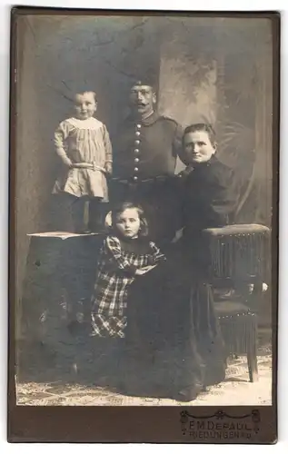 Fotografie F.M. De Paul, Riedlingen a. D., Soldat in Uniform mit Schützenschnur mit seiner Familie im Atelier