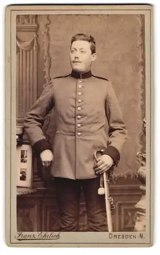 Fotografie Franz Ehrlich, Dresden, Königsbrückerstrasse 50, Soldat mit hängendem Lid und Säbel in Uniform, J-Bat. 12