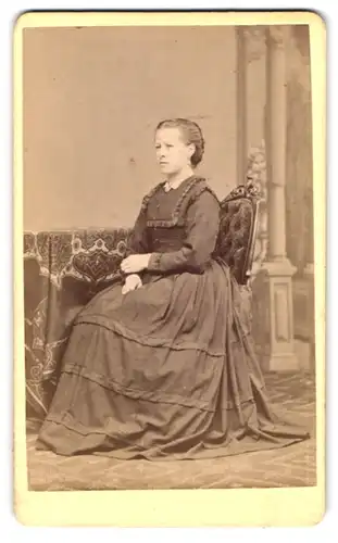 Fotografie Christ. Verra, Deggendorf, junge Dame im schwarzen Kleid auf Stuhl sitzend