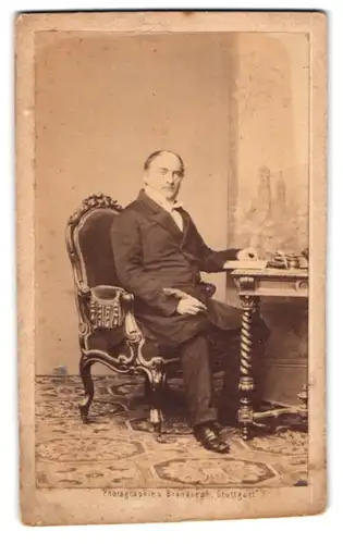 Fotografie Brandseph, Stuttgart, Herr mit Schreibfeder im Anzug am Schreibtisch sitzend