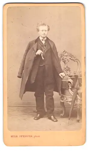 Fotografie Wilhelm Pfeiffer, Reichenberg, Bursche mit Brille im Anzug mit Mantel