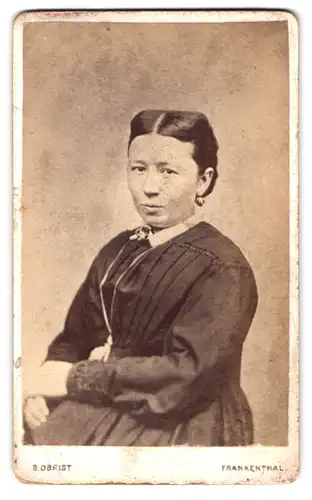 Fotografie B. Obrist, Frankenthal, Portrait junge Frau im gerafften Kleid mit Mittelscheitel