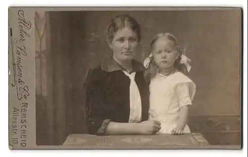 Fotografie Samson & Co., Remscheid, Portrait Mutter mit niedlicher Tochter im weissen Kleid, Zöpfe, Mutterglück