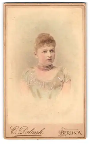 Fotografie O. Delank, Berlin, Friedrichstr. 185, Portrait hübsche junge Frau im Kleid mit Perlenkette, Hand Koloriert