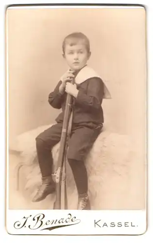 Fotografie J. Benade, Kassel, Königstr., Portrait junger Knabe im Matrosenanzug mit Steinschlossgewehr