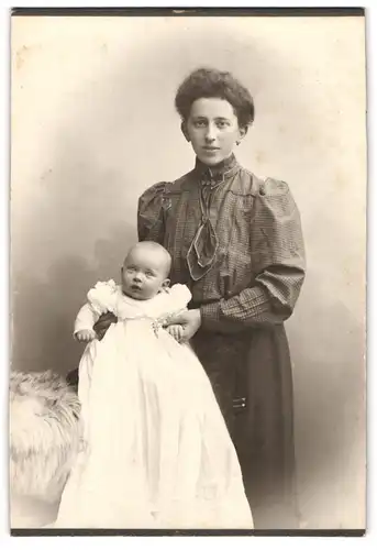 Fotografie unbekannter Fotograf und Ort, junge Mutter in karierter Bluse mit kleiner Tochter im Atelier, Mutterglück