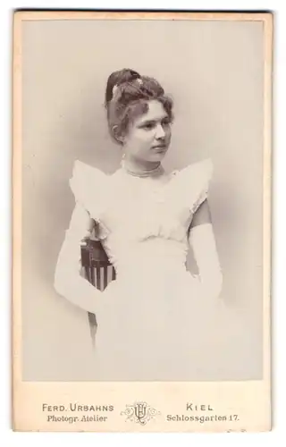 Fotografie Ferd. Urbahns, Kiel, Schlossgarten 17, Portrait junge Frau im weissen Kleid mit Perlenkette und Dutt