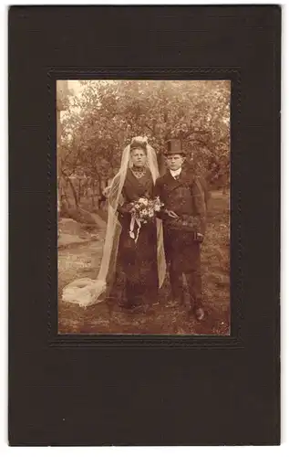 Fotografie unbekannter Fotograf und Ort, Portrait Brautpaar im schwarzen Hochzeitskleid und Anzug mit Zylinder