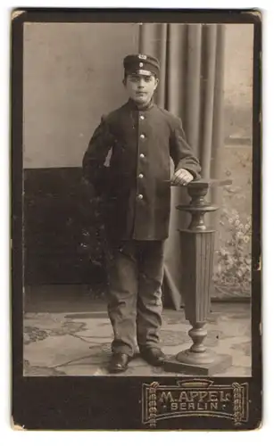 Fotografie M. Appel, Berlin, Hotel-Page in Uniform mit Schirmmütze