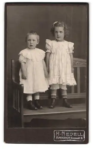 Fotografie H. Nedell, Apenrade, Grossestr. 9, Portrait zwei süsse Mädchen in Kleidern auf einer Bank, Locken