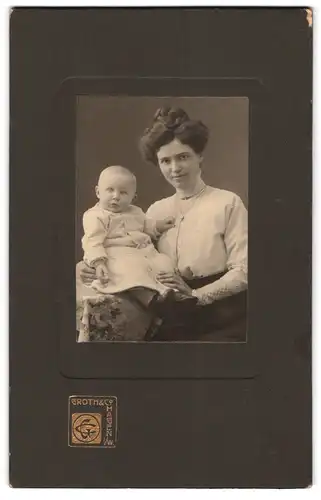 Fotografie Groth & Co., Hagen i. W., Portrait junge Mutter in weisser Bluse mit Kleinkind im Arm, Mutterglück