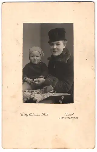 Fotografie Willy Schrader, Zürich, Schützengasse 23, Portrait Mutter im Wintermantel mit Kleinkind auf dem Tisch