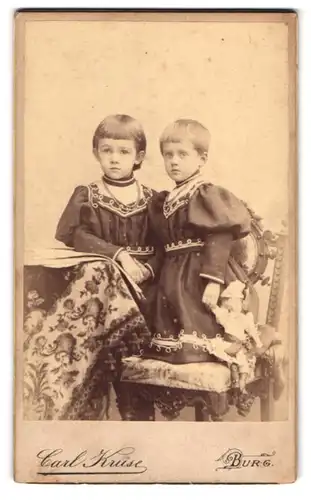 Fotografie Carl Kruse, Burg, Schartauer-Str. 16, Zwei kleine Mädchen mit Puppe tragen verzierte Kleider
