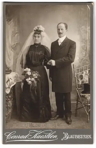 Fotografie Conrad Kaestlen, Blaubeuren, Portrait junges Paar in Hochzeitskleidung mit Blumenstrauss