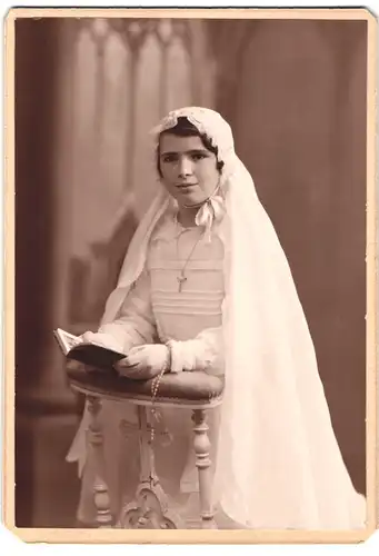 Fotografie unbekannter Fotograf und Ort, Portrait hübsche Frau im Kommunionskleid mit Schleier und Bibel, Gebetspult