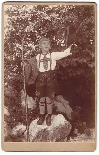 Fotografie unbekannter Fotograf und Ort, Portrait Knabe in bayrischer Tracht mit Lederhose und Jacke, langer Wanderstock