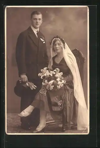 AK Hochzeitspaar in festlicher Kleidung, Bräutigam hält Zylinder in der Hand, Braut mit Schleier und Blumenstrauss