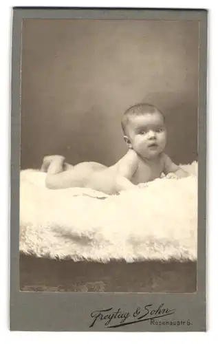 Fotografie Freytag & Sohn, Nürnberg, Rosenaustrasse 6, Portrait nackiges Kleinkind liegt bäuchlings auf Fell