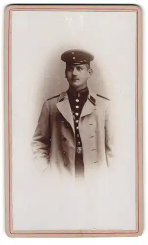 Fotografie unbekannter Fotograf und Ort, Portrait Soldat im Uniformmantel mit Schirmmütze