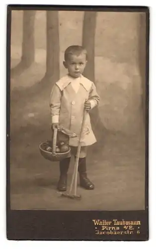 Fotografie W. Taubmann, Pirna a. E., Jacobäerstrasse 6, Portrait kleiner Junge mit Korb u. Rechen