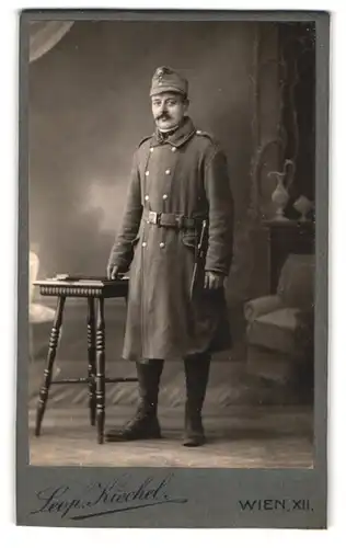 Fotografie Leop. Kiechel, Wien, Schönbrunnerstrasse 226, Soldat im Mantel mit Bajonett