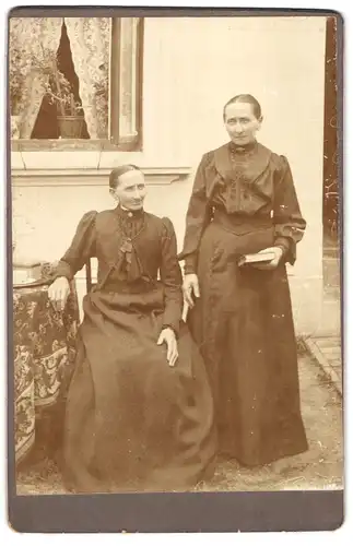 Fotografie unbekannter Fotograf und Ort, Portrait zwei ältere Damen in Kleidern mit Buch