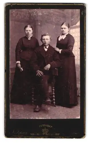 Fotografie N. Jensen, Skive, Mann sitzt zwischen zwei Frauen
