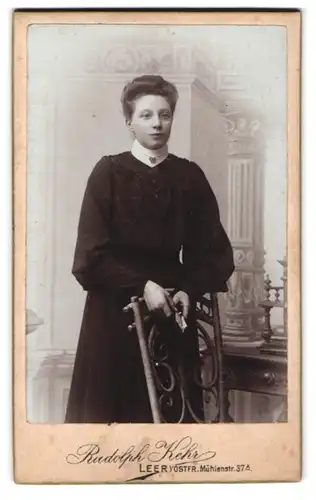 Fotografie Rudolph Kehr, Leer, Mühlenstrasse 37a, Dame mit schwarzem Kleid lehnt an Stuhl