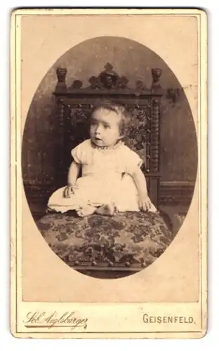 Fotografie Seb. Aiglsburger, Geisenfeld, Baby mit weit geöffneten Augen sitzt auf einem Stuhl