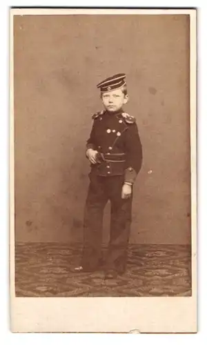 Fotografie Franz Kohn, Zerbst, Portrait junger Knabe in Ulanen Uniform mit Epauletten und Krätzchen