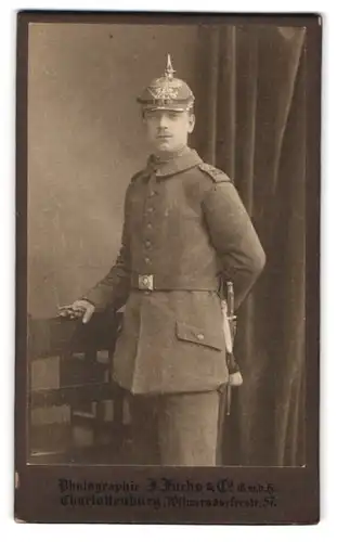 Fotografie J. Fuchs & Co., Berlin, Wilmersdorferstr. 57, Portrait Soldat in Feldgrau mit Ersatz Pickelhaube und Bajonett