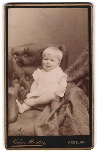 Fotografie Gebr. Martin, Augsburg, Bahnhof-Str., Portrait süsses Kleinkind im weissen Hemd mit nackigen Füssen