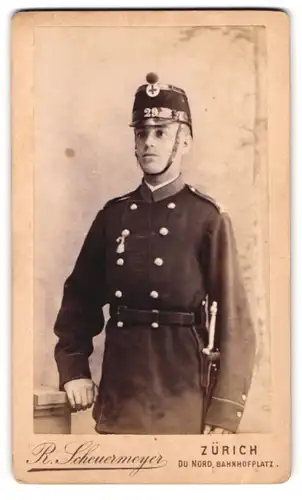 Fotografie R. Scheuermeyer, Zürich, Bahnhofsplatz, Portrait junger schweizer Soldat in Uniform Rgt. 29 mit Bajonett