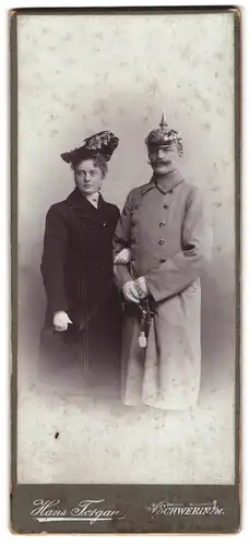 Fotografie Hans Torgau, Schwerin i. M., Offizier in Uniform mit Mantel & Pickelhaube nebst Gattin